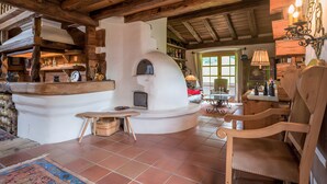 A rustic interior with a stone oven, wooden furniture, and a tiled floor.