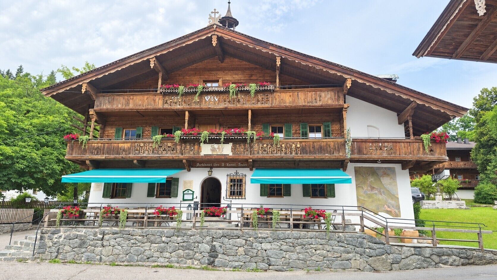 A traditional wooden building with a balcony, stone steps, and a sign indicating it is a restaurant.