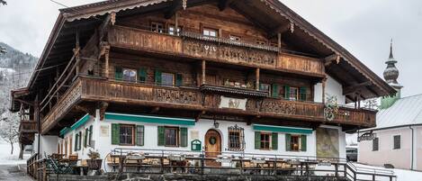 Un edificio de madera tradicional con balcones, una escalera de piedra y un letrero que indica un restaurante.