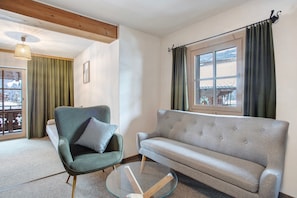 Una sala de estar con un sofá, un sillón y una mesa de centro de vidrio.
