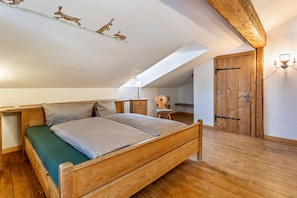 Um quarto com uma cama de madeira, uma escrivaninha e uma cadeira.