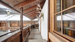 Un balcon en bois offrant une vue sur des bâtiments enneigés et un plafond en bois.
