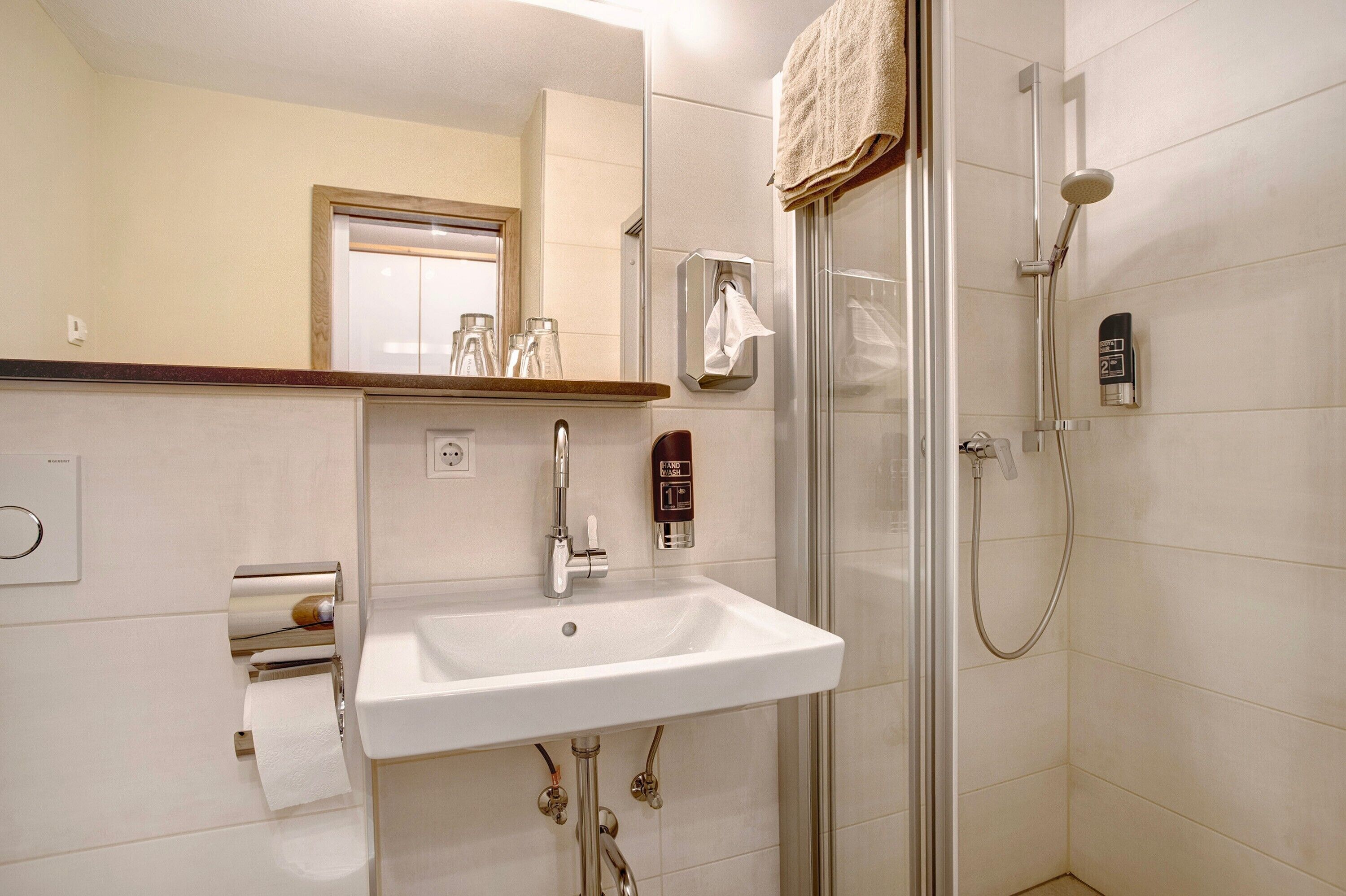 A bathroom with a sink, mirror, towel rack, and shower.