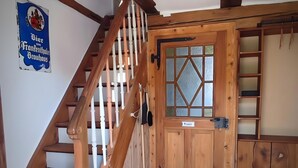 A wooden staircase with a white railing, a wooden door with glass panels, and a patterned floor. - Apartment 'La Maison Palatinate' with Charm, Southern Wine Route (Kapsweyer)
