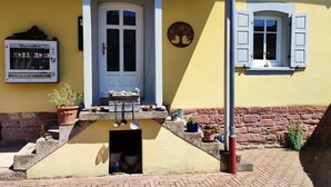 A yellow building with a door, a window with shutters, and a wall-mounted sign. - Apartment 'La Maison Palatinate' with Charm, Southern Wine Route (Kapsweyer)