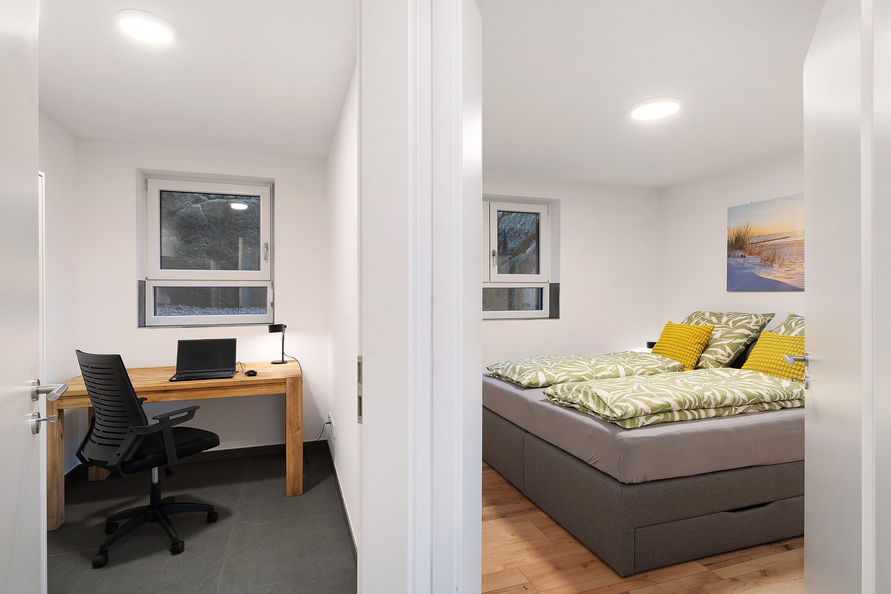 A bedroom with a bed, a desk with a laptop, and a chair.