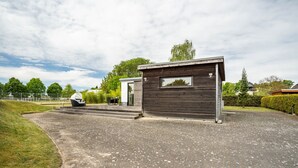 Un bâtiment moderne à la façade sombre, doté d’une petite fenêtre et d’un espace d’entrée pavé.