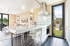 A modern kitchen with a large island, stainless steel appliances, and a sliding glass door to the outdoors.