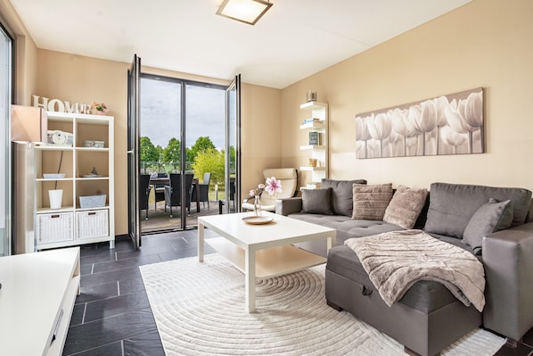A modern living room with a sofa, coffee table, and a bookshelf.