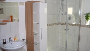 Un bagno con cabina doccia in vetro, un lavandino bianco e uno specchio sopra.