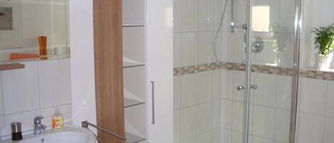 A bathroom with a glass shower enclosure, a white sink, and a mirror above it.
