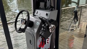 Die Kommandostation eines Bootes mit Steuer, Gashebel und verschiedenen Bedienelementen.