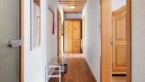 Un couloir avec des portes en bois, un radiateur blanc et un étagère en métal.