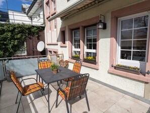 Une terrasse extérieure avec une table et des chaises, une antenne parabolique et des plantes en pot.