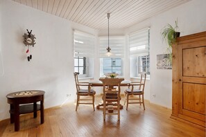 Un coin repas avec une table en bois, quatre chaises, une horloge et un luminaire suspendu.