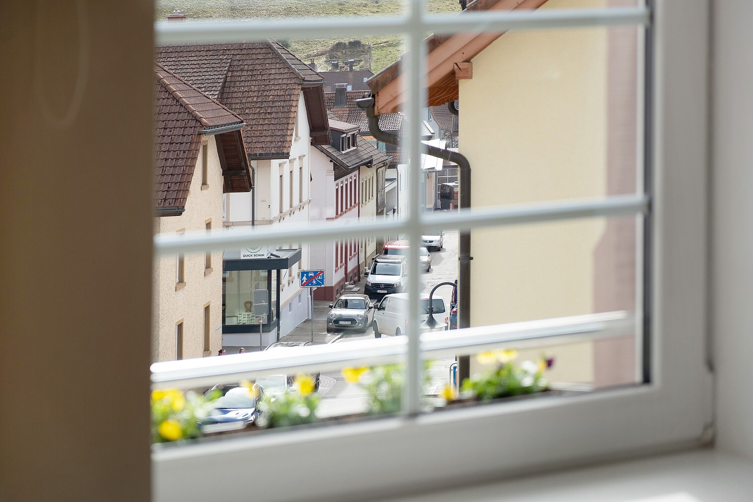 A window view of a street with buildings, cars, and a sign for a restaurant.