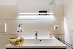 A modern bathroom with a white sink, a mirror, a towel, and a flower. - Apartment 'Ferienwohnung Silberbergblick' with Wi-Fi (Todtnau)