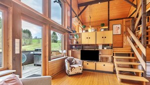 Ein Holzinnenraum mit einer Couch, einem Fernseher, Holzschränken und einer Treppe.
