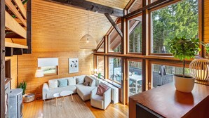 Ein modernes Interieur mit Holzbalken, großen Fenstern, einer Sofagarnitur und einem Kamin.