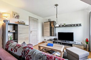 Una sala de estar moderna con un sofá, una mesa de centro, un televisor y una estantería.