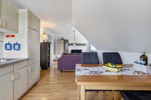 Una cocina moderna con armarios de madera, una mesa de comedor y un sofá morado.