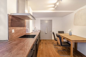 A compact kitchen with a wooden countertop, a built-in stove, and a dining area with a table and chairs.