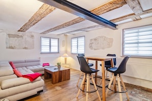 Une pièce comprenant un canapé, une table basse, une table à manger avec des chaises et de grandes fenêtres.