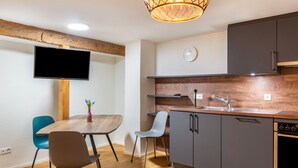 A modern kitchen with a wooden countertop, grey cabinets, a built-in oven, and a flat-screen TV mounted on the wall. - Apartment '3' in Bodman-Ludwigshafen (Bodman-Ludwigshafen)