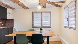 A dining area with a wooden table, two chairs, a potted plant, and a window with blinds. - Apartment '2' in Bodman-Ludwigshafen (Bodman-Ludwigshafen)