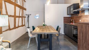 A modern kitchen with a wooden table, chairs, and a built-in oven. - 'Family Apartment 6' (Bodman-Ludwigshafen)