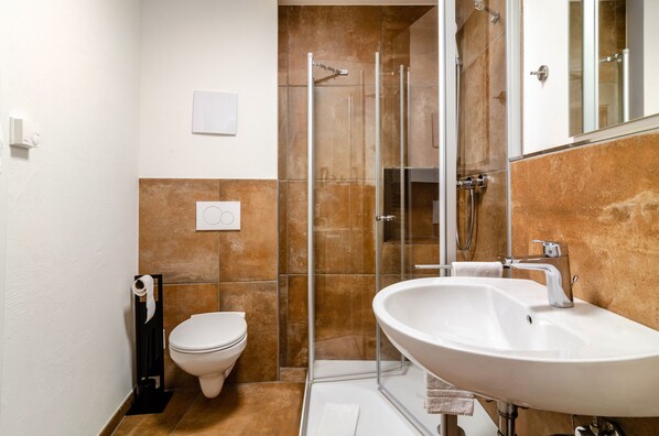 Un baño con inodoro, lavabo, ducha y espejo.