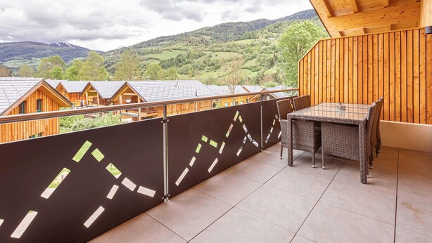 Un balcón de madera con vistas a un paisaje montañoso.