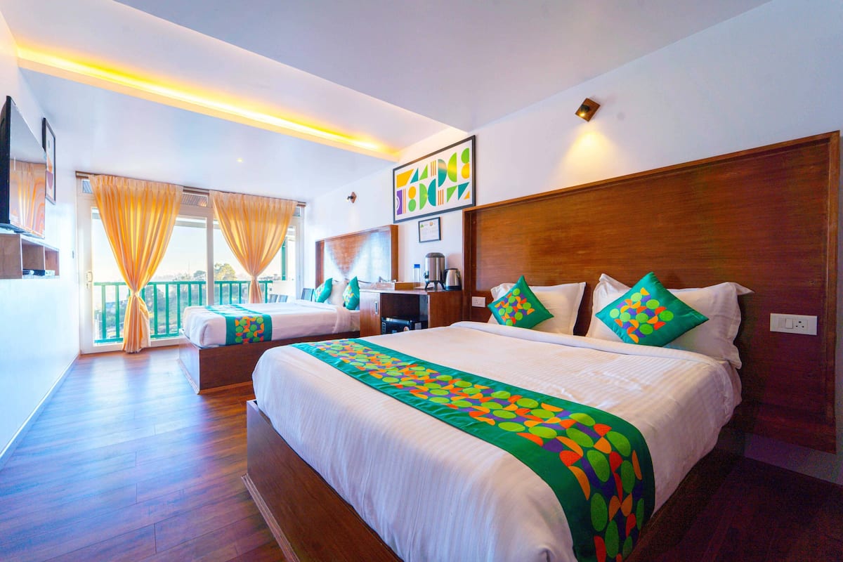 Quarto de hotel com duas camas, varanda e vista para a cidade.
