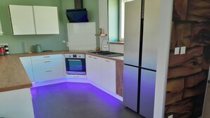 Una cocina moderna con armarios blancos, horno empotrado y refrigerador.