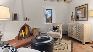 Un salon chaleureux avec une cheminée, un canapé, un fauteuil et un meuble.