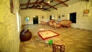 Une pièce spacieuse avec un plancher en bois, des meubles en osier et une table de ping-pong.
