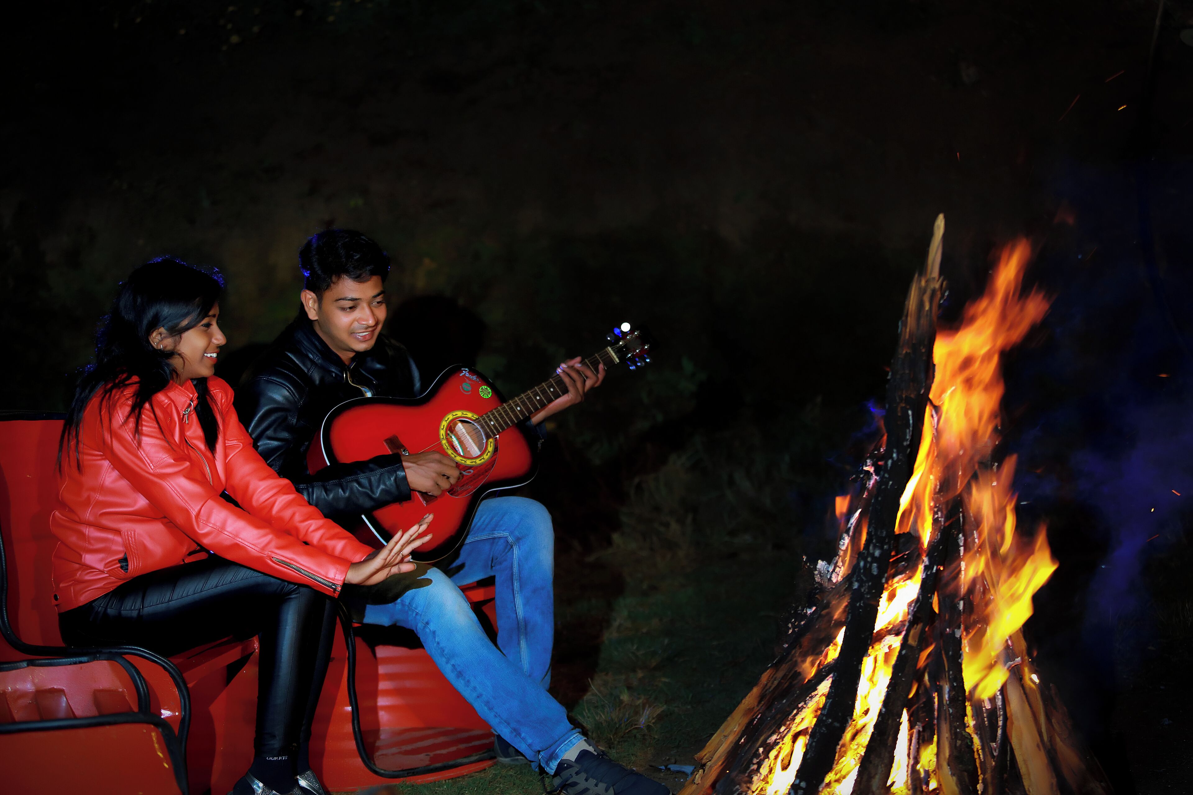 Two people sitting by a campfire.