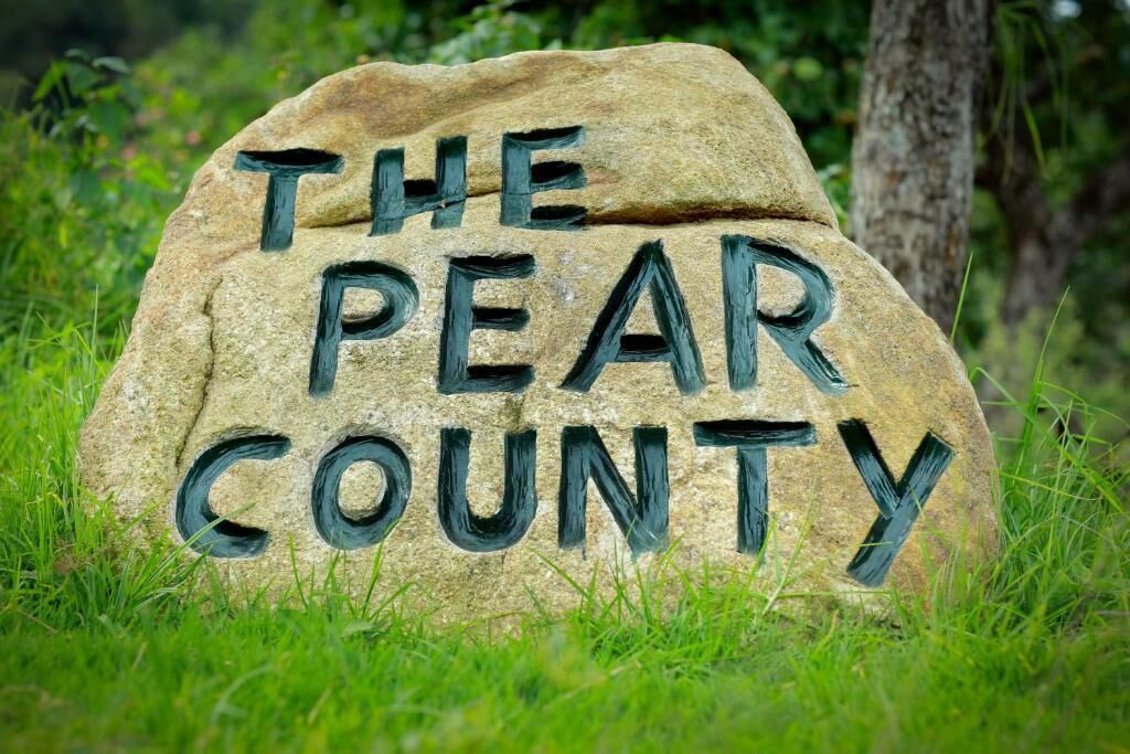 A stone sign with the text "THE PEAR COUNTY" in black paint.