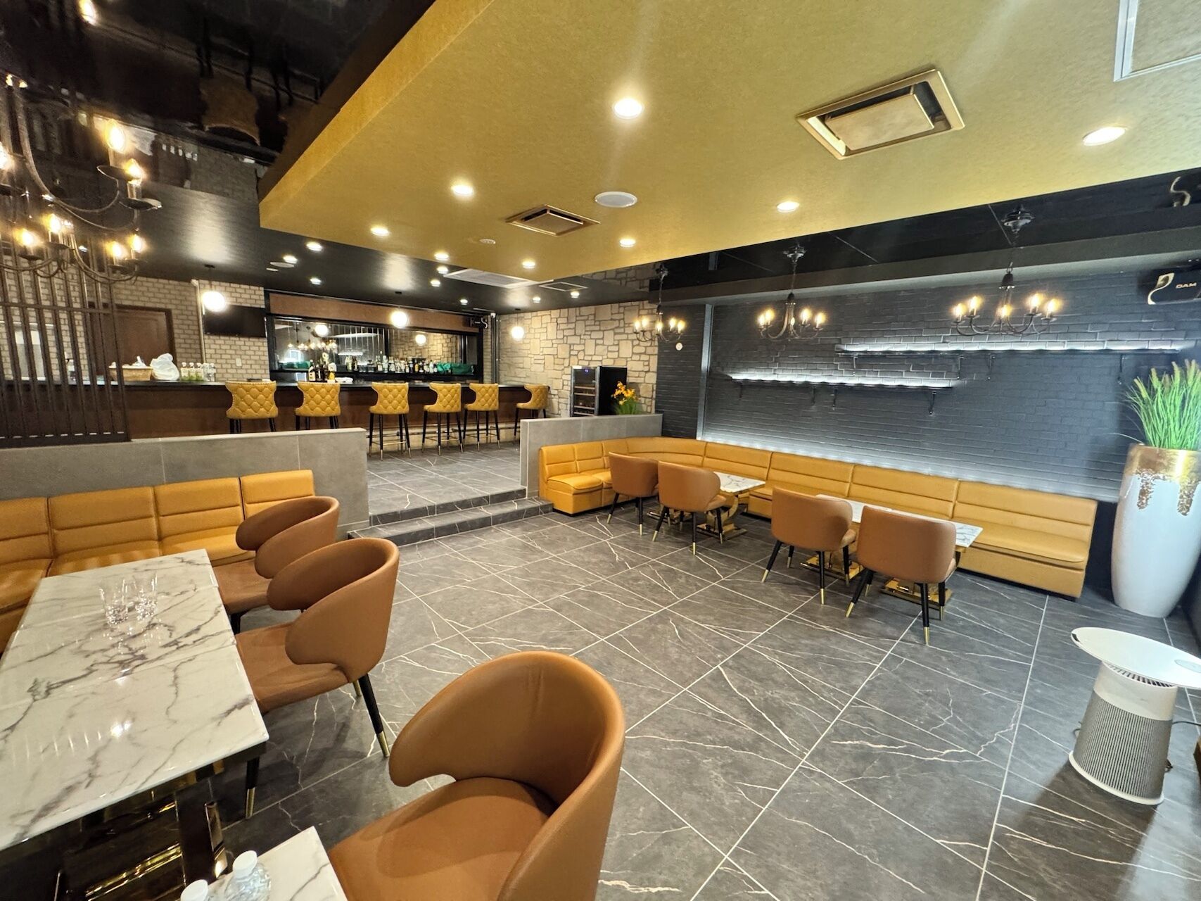 A modern restaurant interior with a bar area, seating arrangements, and a decorative wall.