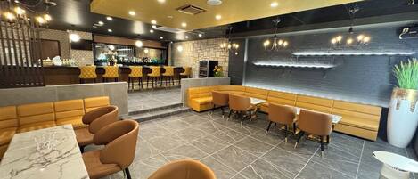 A modern restaurant interior with a bar area, seating arrangements, and a decorative wall.