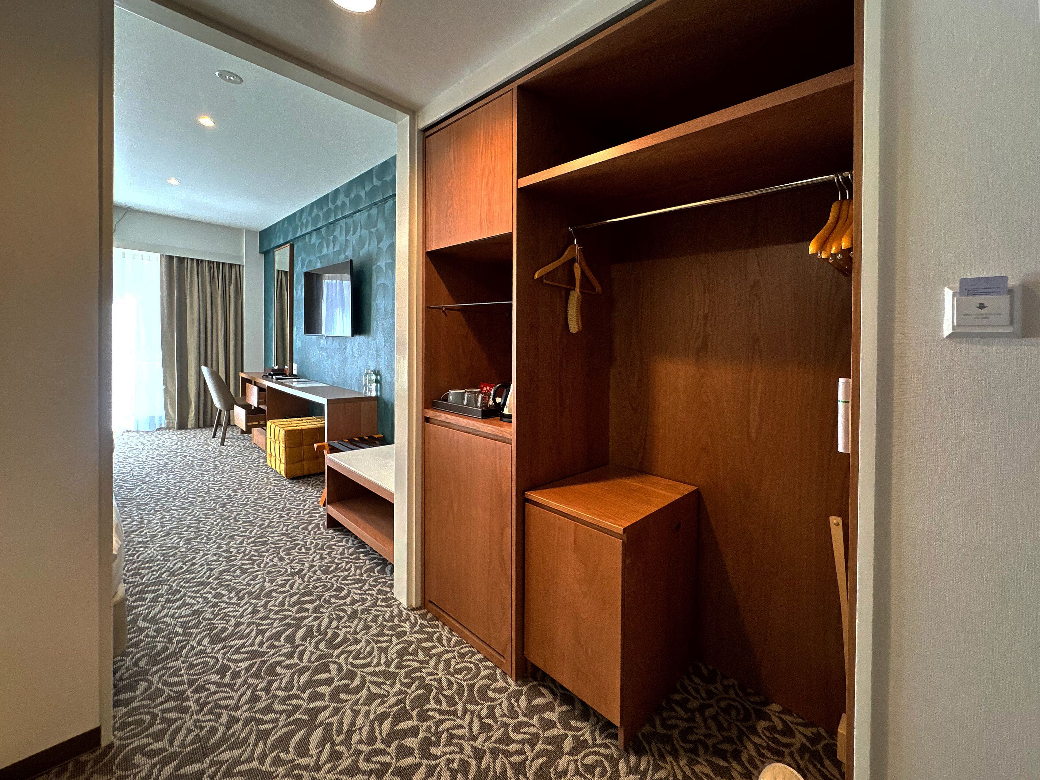 A hotel room with a walk-in closet, a desk, and a seating area.