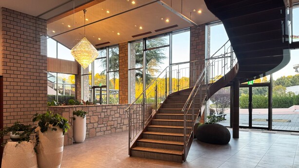Eine geräumige Lobby mit Treppe, großen Fenstern und Topfpflanzen.