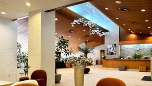 Eine moderne Lobby mit Empfangstresen, Sitzgelegenheiten und einer großen Pflanze.