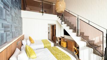 A modern hotel room with a large bed, a desk, a chair, and a staircase.