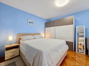 Une chambre à coucher comprenant un lit, des tables de chevet, une commode, un miroir et un tableau accroché au mur.