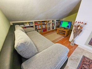 Una sala acogedora con sofá, estantería y televisor.