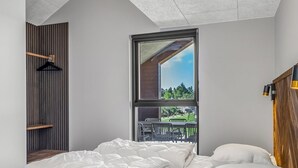 A bedroom with a large window, a wooden slat wall, and a bed with white bedding. - "Sönke" - 4km from the sea by Interhome (Rømø)