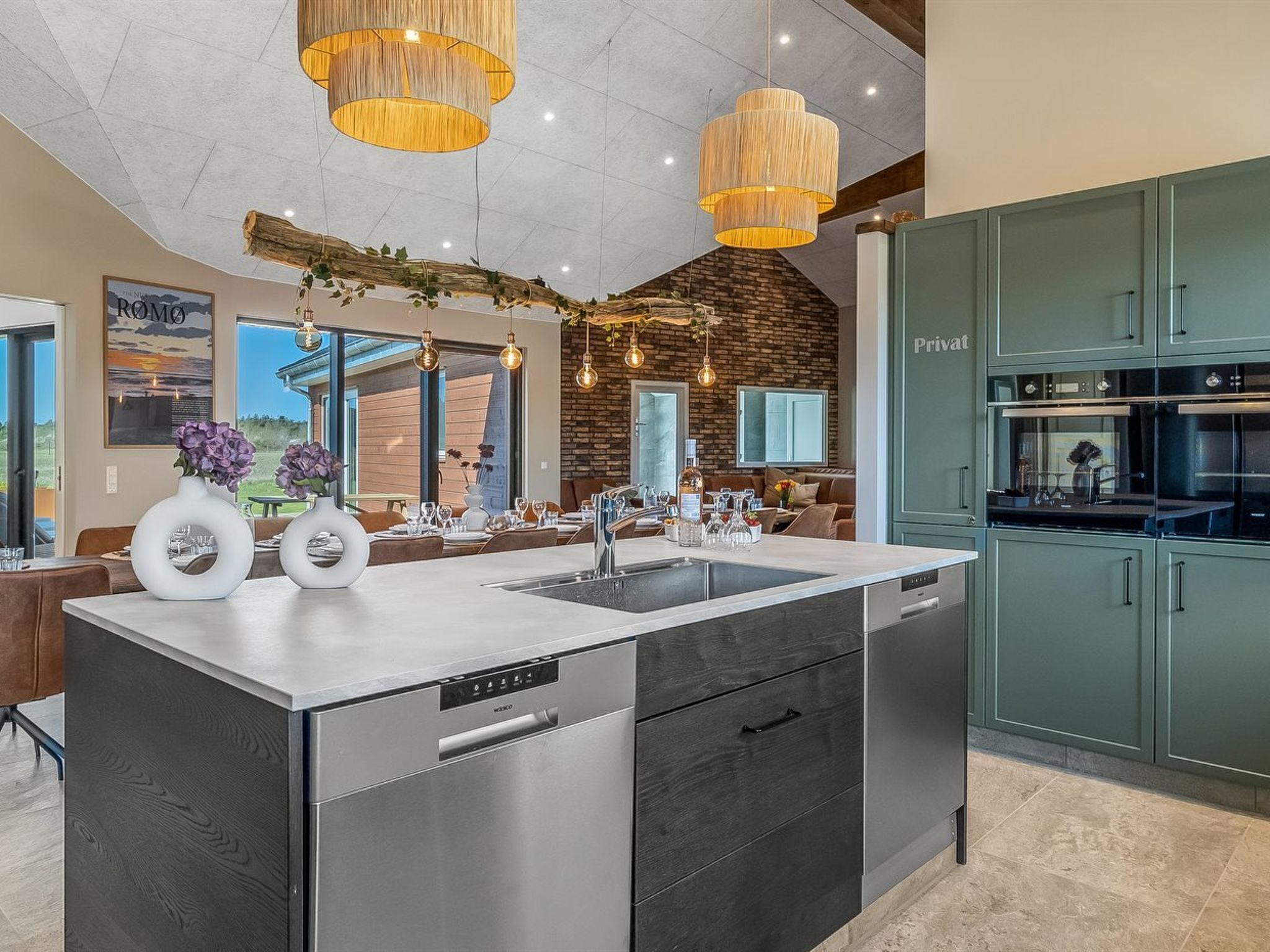 Una cocina moderna con una isla central, electrodomésticos de acero inoxidable y vistas al exterior.