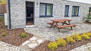 A modern building with a stone facade, a wooden door, and a picnic table in the courtyard. - Markéta by Interhome (Smržovka)