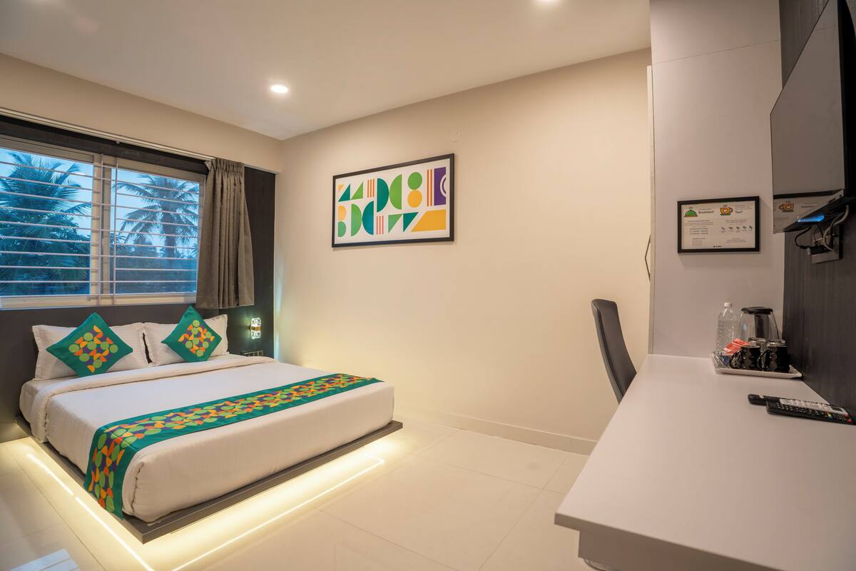 A hotel room with a bed, a desk, a chair, and a window with curtains.